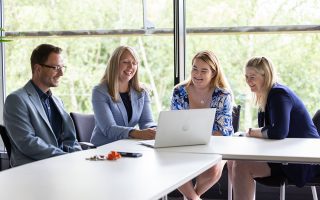 Employees sat at a desk looking at a laptop