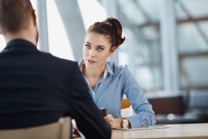 woman in blue shirt speaking to man in suit